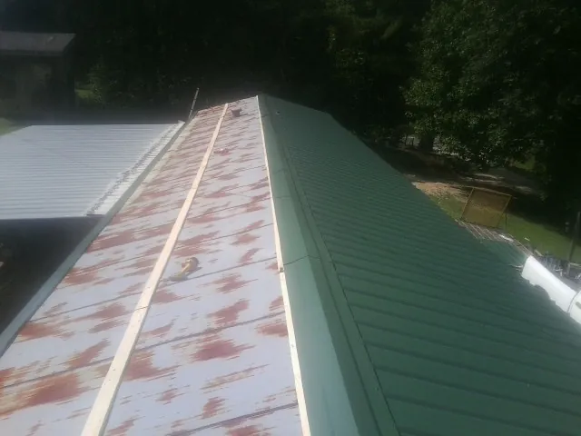 Old rusted panels beside newly installed green metal roofing — Wind Damage Roof Repair by Roofing Brothers in Van Nuys