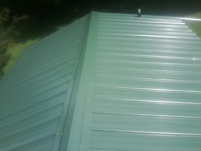 New green metal panels meeting at the ridge of a roof — Flat Roof Repair work by our crew in Van Nuys
