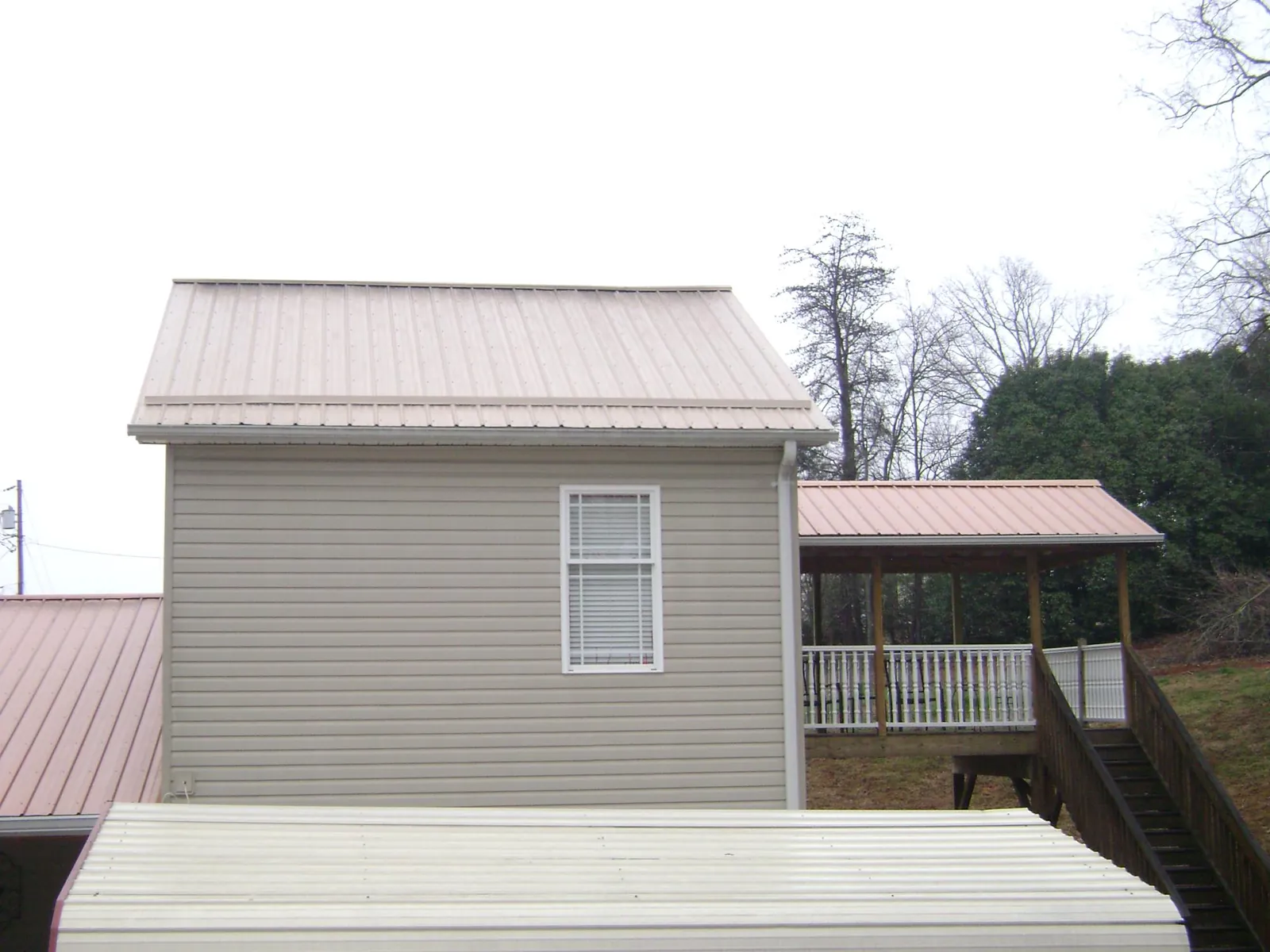 Tan metal roofs on a two story addition and attached porch, from a Roof Replacement job in Van Nuys
